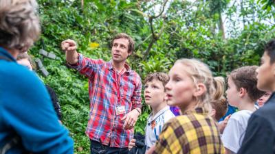 A group of school pupils standing looking in the direction of the teacher who is pointing